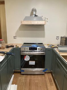 an oven in the middle of a kitchen being remodeled with wood flooring and cabinets