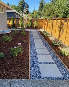 a garden with gravel and rocks in the middle, along side a fenced yard