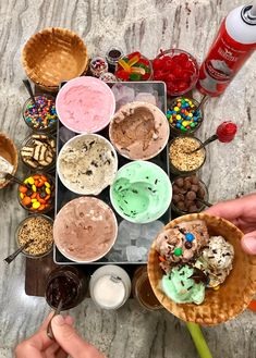 ice cream sundaes and desserts are arranged on a marble countertop with hands holding spoons