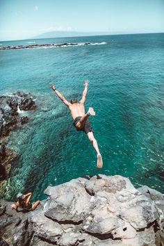 a man diving into the ocean from a cliff