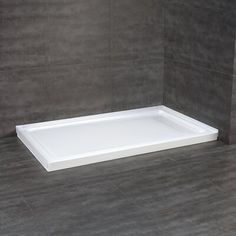 a white square shower tray on the floor in a bathroom with grey walls and tile