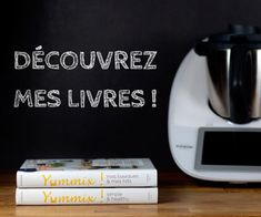 there is a coffee maker and two books on the table next to it, which reads decouvez mes livres