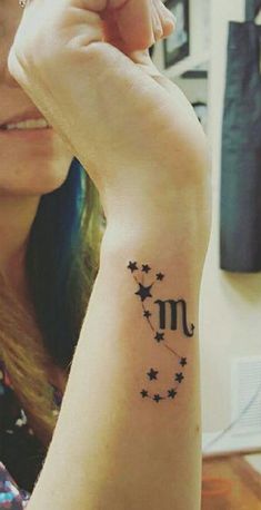 a woman with a tattoo on her arm that has the letter m and stars in it