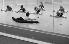 a group of young children sitting on the floor in front of mirrors doing ballet exercises