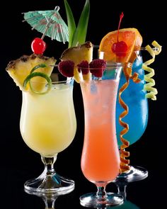 three different types of cocktails in glasses on a reflective surface with black back ground