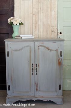 an old white cabinet with flowers and books on top