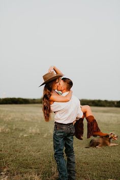 a man and woman hug in the middle of a field