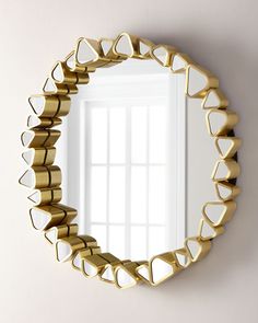 a mirror that is on the wall with some gold hearts around it and a window in the background