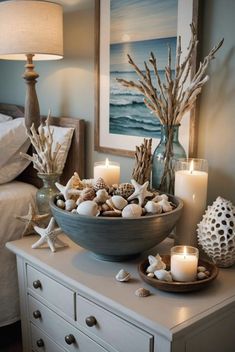 a bowl filled with seashells and candles on top of a dresser next to a bed