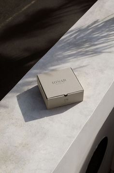 a box sitting on top of a white table next to a tree and building in the background