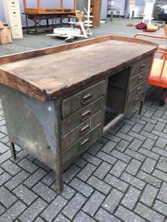 an old wooden desk sitting on top of a brick floor