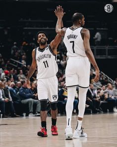 two basketball players are high fiving each other on the court with their hands in the air