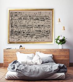 a bed with sheet music on it in front of a wall hanging above the bed