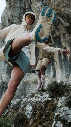 two people standing on top of a rocky hill with their feet in the air and one person holding a frisbee