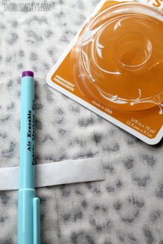 a blue pen sitting on top of a piece of paper next to a plastic container