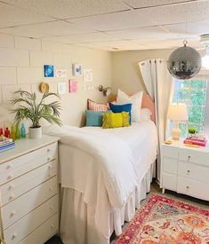 a bed room with a neatly made bed next to a dresser and a rug on the floor