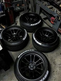 four black rims and tires sitting on the ground