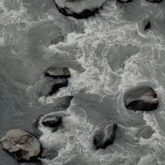 some rocks in the water with white foam on them