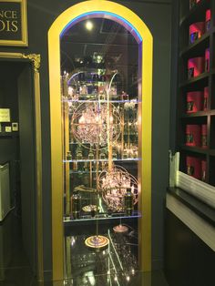 a display case with many items inside of it in a room filled with shelves and glass doors