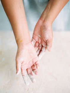 a person holding something in their hands while standing on a counter top with flour all over them