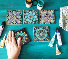 the person is painting decorative tiles on the wooden table with paints and glues to decorate them