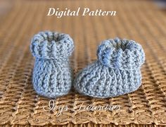 there is a pair of knitted baby booties sitting on a woven tablecloth