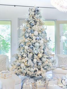 a white christmas tree decorated with silver ornaments