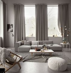 a living room filled with lots of furniture and large windows covered in shades of gray