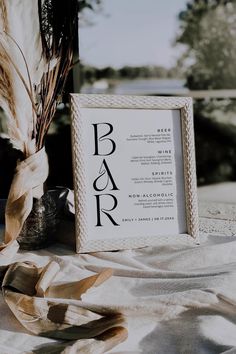 a white frame sitting on top of a table next to a vase filled with flowers