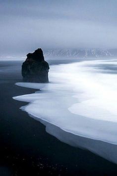 black and white photograph of an ocean with rocks