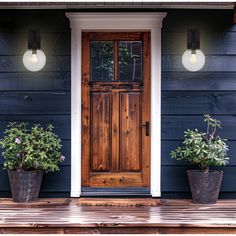 two potted plants sit on the front porch of a blue house with white trim