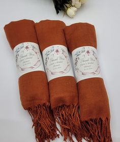 three brown towels with white labels on them sitting next to some flowers and a bouquet