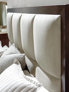 the headboard of a bed with white sheets and pillows