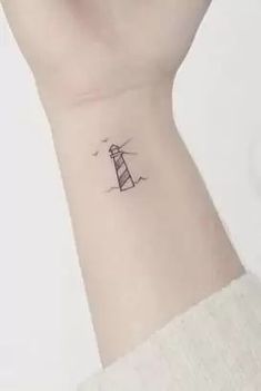 a small lighthouse tattoo on the wrist