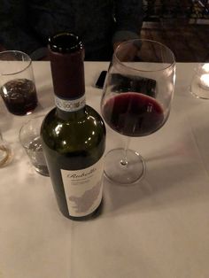 a bottle of wine sitting on top of a table next to two glasses of wine