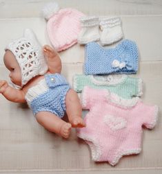 a baby doll laying on top of a wooden floor next to four knitted ones