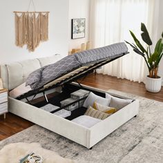 a living room with a white couch and a gray ottoman that is open to reveal the storage compartment