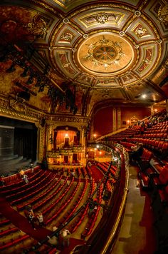 an empty theater with red seats and gold ceiling