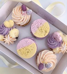 cupcakes decorated with icing and decorations in a box