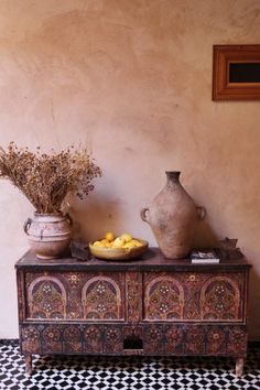 two vases sitting on top of a wooden table next to a bowl of fruit