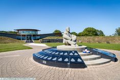 a large statue sitting on top of a cement slab in the middle of a park