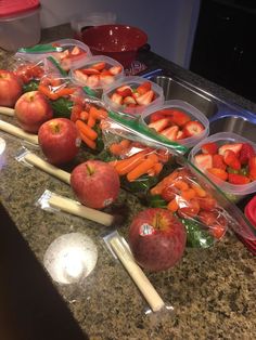 apples, carrots and strawberries in plastic containers on a counter