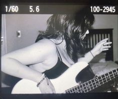 black and white photograph of a woman playing a bass guitar with her hands in the air