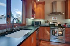 a kitchen with wooden cabinets and stainless steel appliances, including an oven, dishwasher, sink, microwave, and window