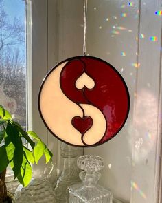 a stained glass yin symbol hanging on a window sill next to a potted plant