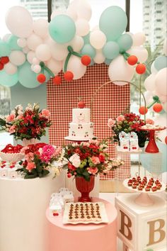 a table topped with cake and flowers next to balloons