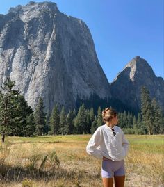 a woman standing in front of a mountain with her back turned to the camera,