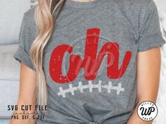 a woman sitting on a couch wearing a gray shirt with the word football in red