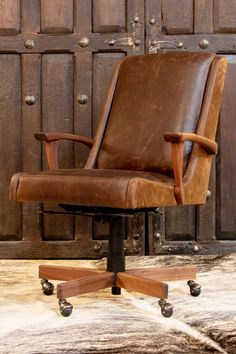 a brown leather office chair sitting on top of a wooden floor next to a wall