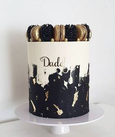 a black and white cake with gold decorations on it's top that says, daddy